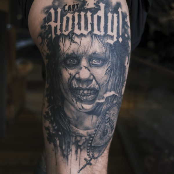 Image of a large black and grey thigh tattoo themed from the exorcist movie