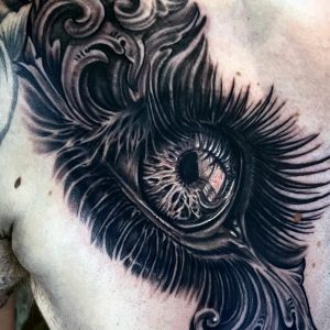 image of a chest tattoo an black and grey eye with filigree design by Jimbo