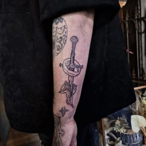 image of an arm tattoo featuring the shards of narsil sword and elven leaf brooch from lord of the rings