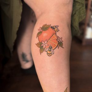 image of a leg tattoo featuring an orange and bees with flowers in a colour whimsical style