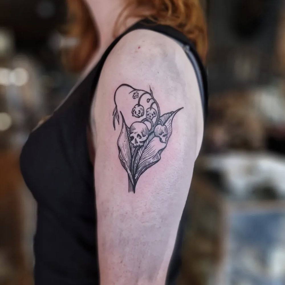 image of an arm tattoo design is of a plant with skulls for flower heads and buds