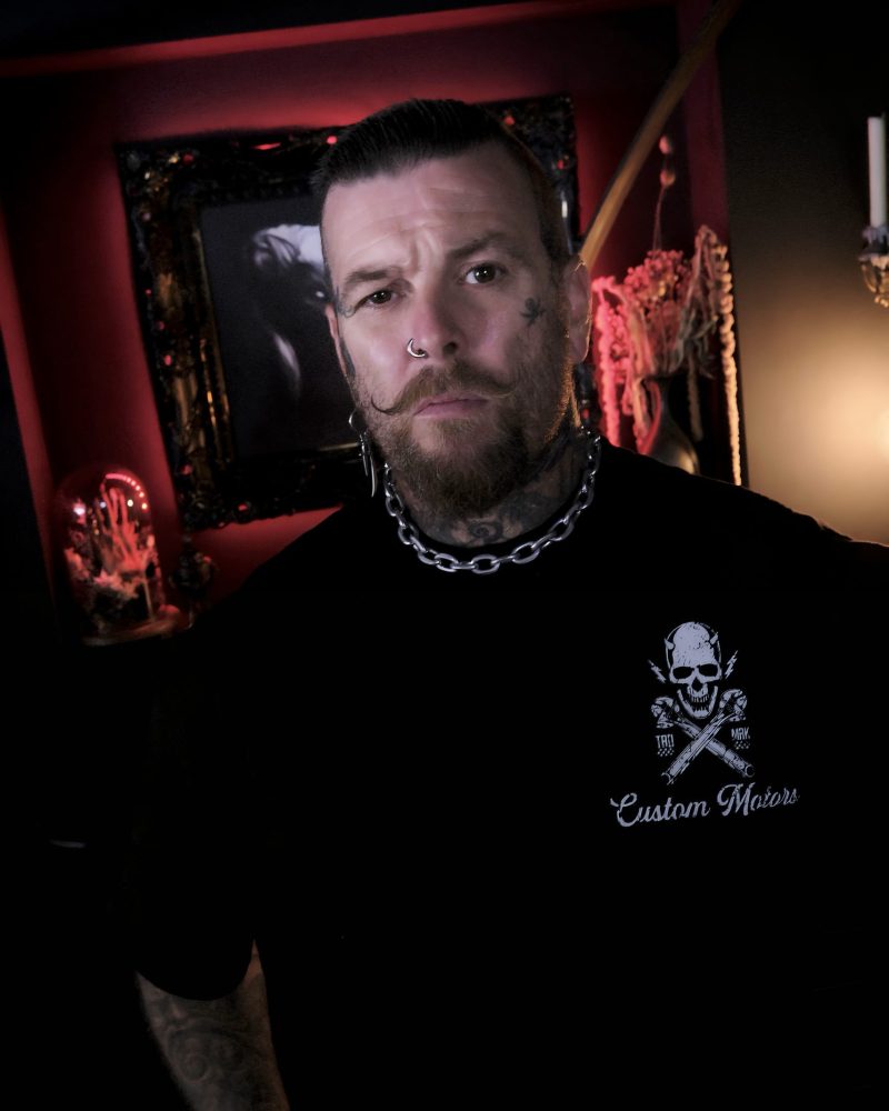 Image of tattoo artist Jimbo from one for sorrow tattoo studio in Shrewsbury taken inside the studio with glowing red background