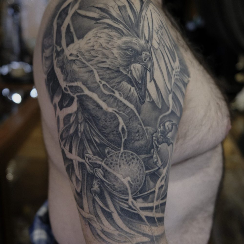 Tattoo of a blazing phoenix with claws grabbing a crystal ball