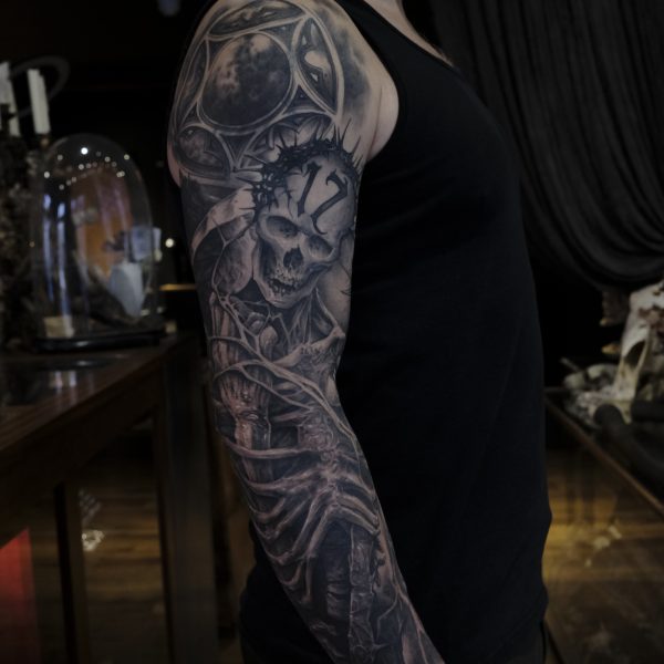 Black and grey tattoo sleeve featuring a custom skeleton and slayer themed artwork