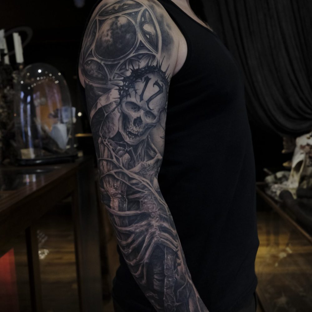 Black and grey tattoo sleeve featuring a custom skeleton and slayer themed artwork