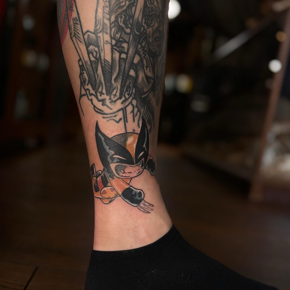 Wolverine Photo shows an ankle tattoo of wolverine done in a pop head comic style