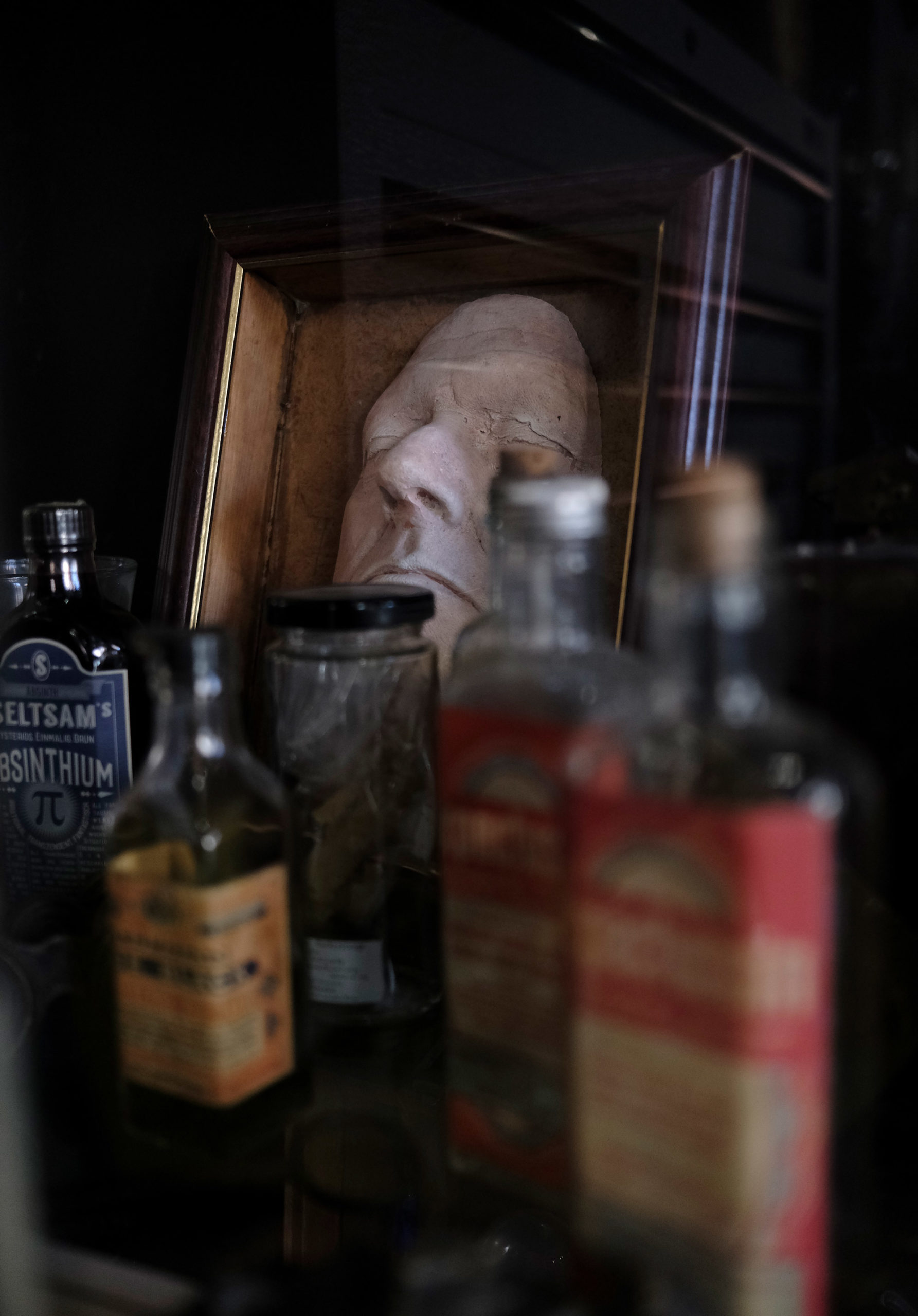 an image f a collection vintage medical bottles with a death mask in the background