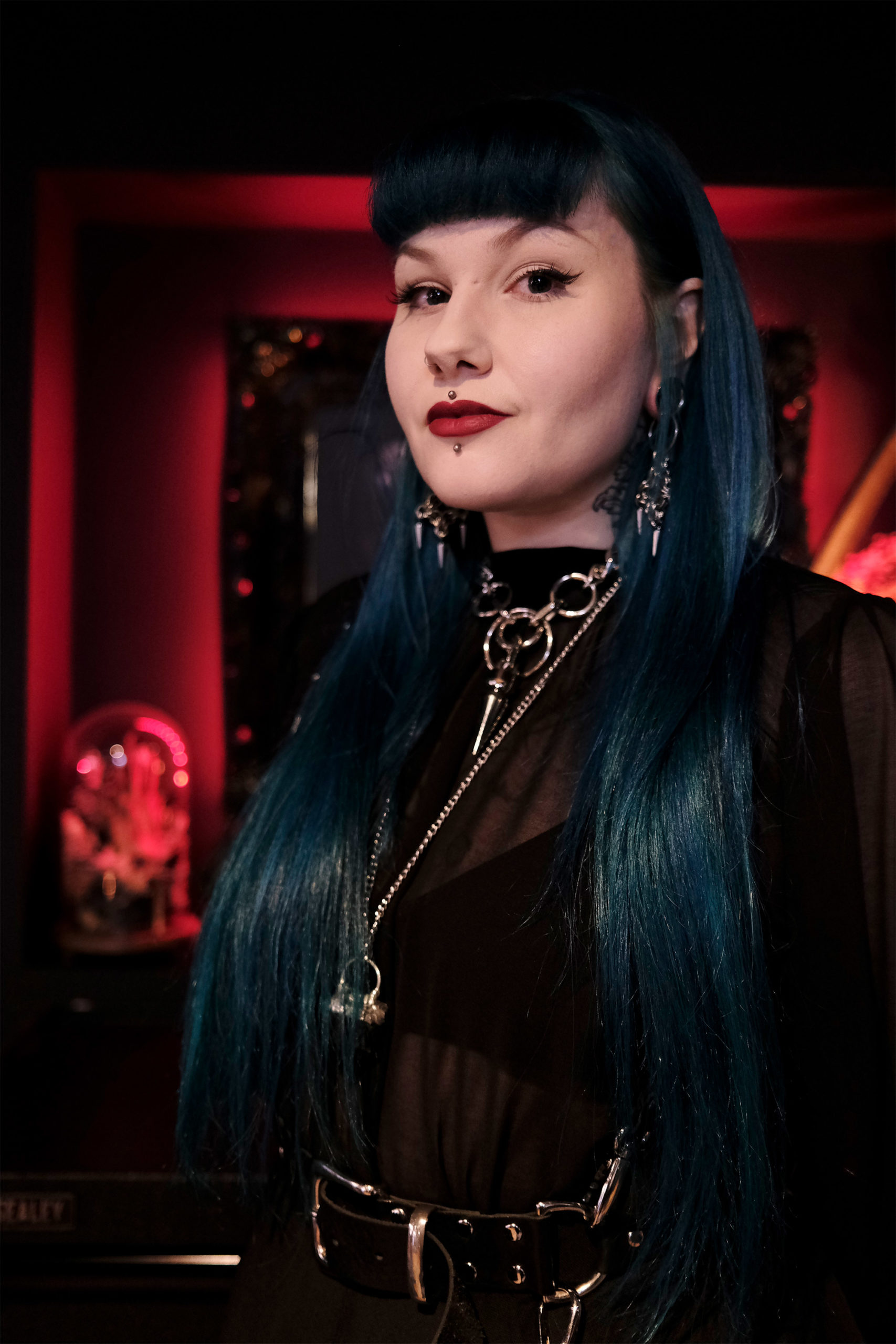 Sarah-Jemimah-Portrait Image showing a headshot of tattoo artist Sarah Jemimah who has long blue hair and full fringe wearing black with silver jewellery