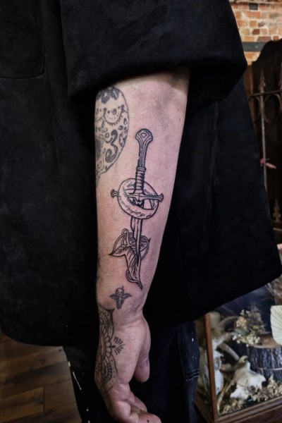 image of an arm tattoo featuring the shards of narsil sword and elven leaf brooch from lord of the rings