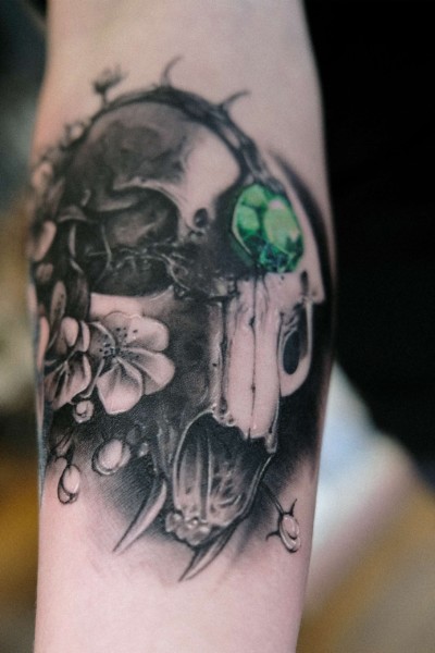 image of a tattoo featuring a cat skull, flowers and green jewel in the middle of the cat skull forehead all done in a soft black and grey style