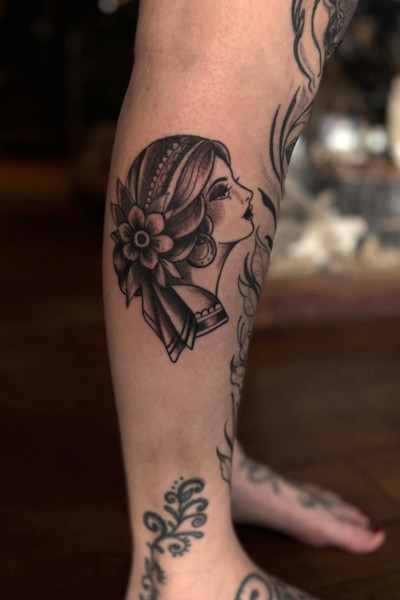 Ladyface Photo shows a leg with a tattoo of a neo traditional lady face design