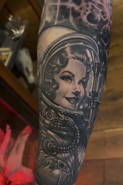 Image of a black and grey tattoo featuring a classic 60's style woman in a spacesuit